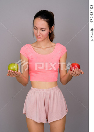 Young beautiful woman holding red apple and green apple 47248438
