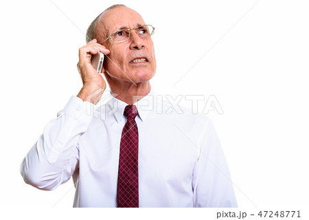 Studio shot of senior businessman talking on mobile phone while Studio shot of senior businessman talking on mobile phone while 47248771