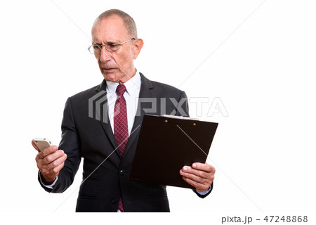 Studio shot of senior businessman holding clipboard while using  47248868