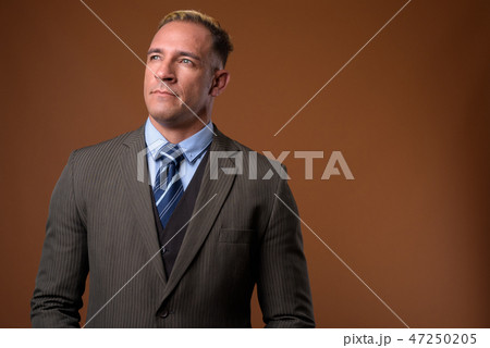 Studio shot of businessman against brown background 47250205