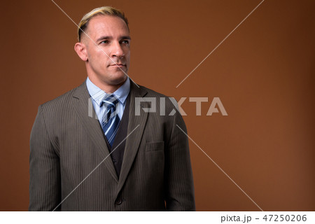 Studio shot of businessman against brown background 47250206