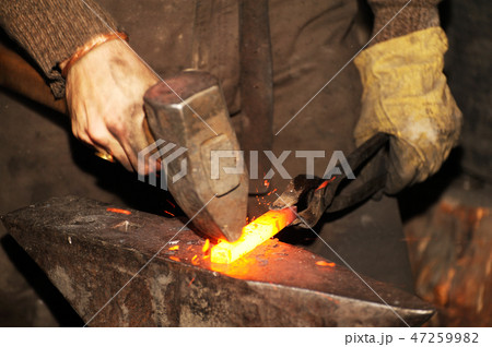 Blacksmith working metal with hammer on the anvil 47259982