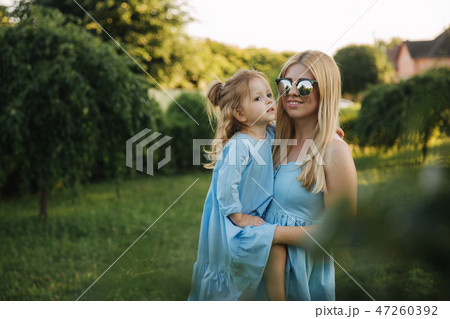 Young beautiful woman with her little cute daughter. Young daughter hugs mother in summer park 47260392