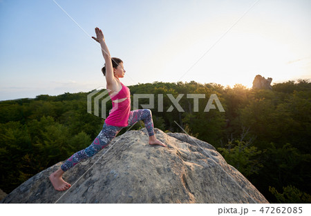 Attractive slim girl doing stretching yoga exercises on top of huge rock 47262085