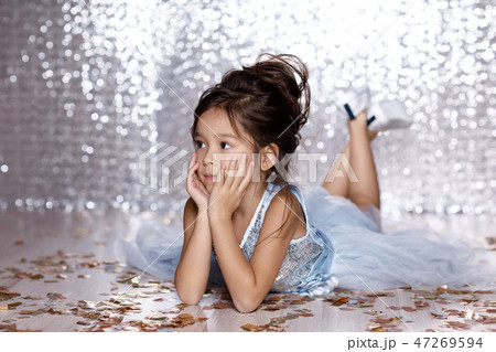 little girl in blue dress sitting on the floor with confetti 47269594