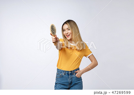 young beautiful woman combing her hair isolated over grey background. young beautiful woman combing her hair isolated over grey background. 47269599