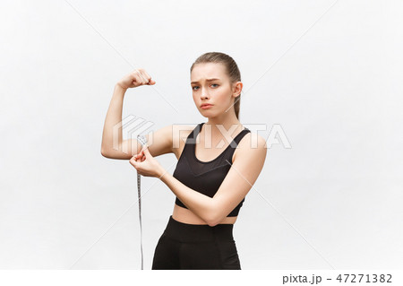 Portrait of an upset sad woman holding measuring tape looking at camera isolated over white 47271382