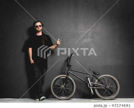 Man standing next to his BMX bike, pointing his finger. Man standing next to his BMX bike, pointing his finger. 47274691