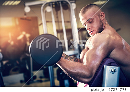 Muscular man working out at a gym. Muscular man working out at a gym. 47274773
