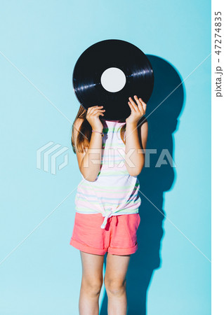 Little girl holding a vinyl disc against her head. 47274835