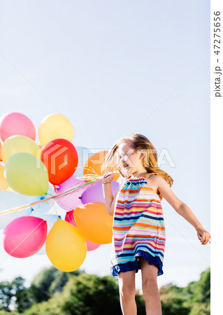 Happy girl running with a bunch of colorful balloons. Happy girl running with a bunch of colorful balloons. 47275656
