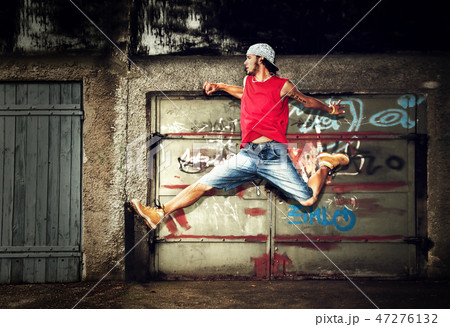 Young man jumping on grunge wall Young man jumping on grunge wall 47276132