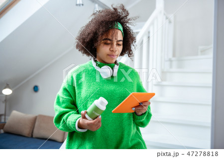 Curious young lady checking ingredient of her vitamins 47278818
