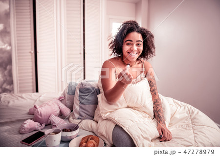 Smiling cheerful lady with curly hair carrying chocolate cereal 47278979