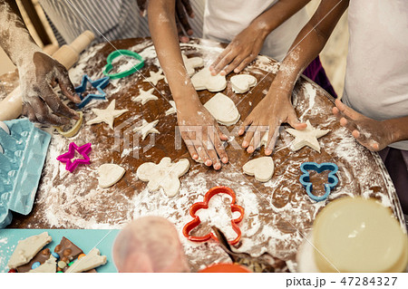 Little helpful daughters joining their father while making cookies 47284327