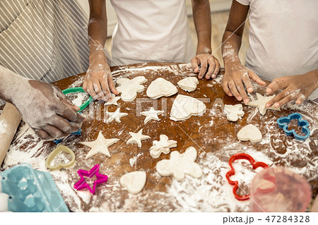 Father and daughters standing near table after forming cookies Father and daughters standing near table after forming cookies 47284328