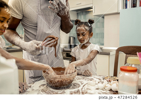Two daughters feeling cheerful while making chocolate pie 47284526