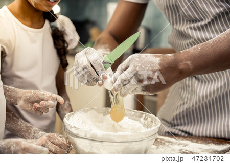 Father wearing striped apron beating eggs making cupcakes 47284702