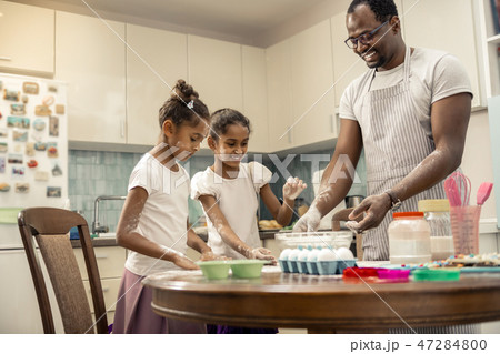 Two funny girls cooking pie with their loving helpful father Two funny girls cooking pie with their loving helpful father 47284800