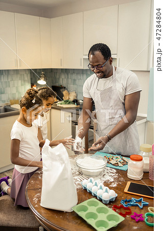 Father and daughters feeling amazing cooking pie for mother together Father and daughters feeling amazing cooking pie for mother together 47284804