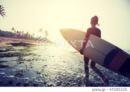 Woman surfer walking with surfboard on coral reefs 47285228