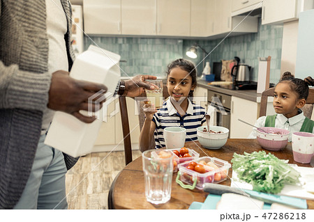 Caring father giving glass of pineapple juice to his daughter 47286218