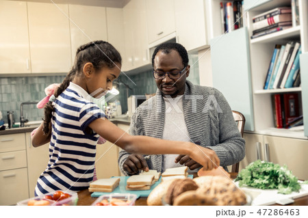Helpful daughter with nice hairstyle helping father in kitchen 47286463