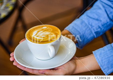 Hands holding coffee cup flower on coffee cup. Hands holding coffee cup flower on coffee cup. 47286930