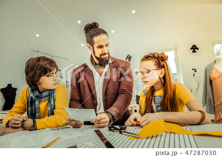Fashion designer wearing jacket and little scarf speaking with children 47287030