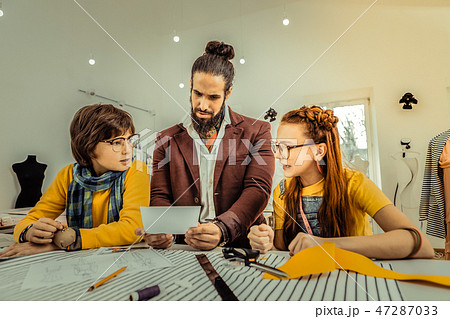 Children and fashion designer looking at photo of model 47287033