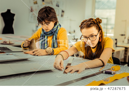 Red-haired girl wearing glasses and massive earrings using ruler Red-haired girl wearing glasses and massive earrings using ruler 47287675