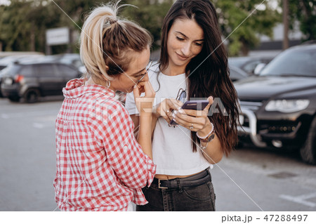 Two beautiful young women are looking at a smartphone 47288497