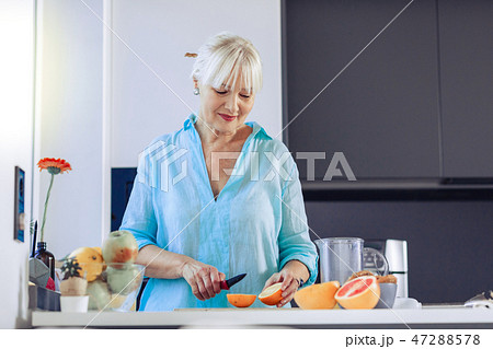 Positive aged woman looking at the orange Positive aged woman looking at the orange 47288578