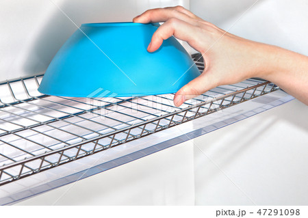 Hand takes bowl from kitchen cupboard  47291098