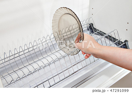 hand takes dish from inside wire plate drainer. hand takes dish from inside wire plate drainer. 47291099