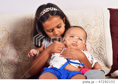 Sister hugging happy baby brother sitting on sofa Sister hugging happy baby brother sitting on sofa 47292155