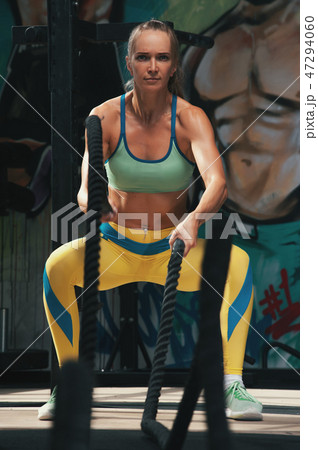 Portrait of sporty woman training with battle ropes 47294060