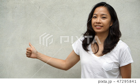 Mixed race Asian girl thumb up concrete background Mixed race Asian girl thumb up concrete background 47295841