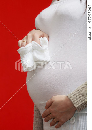 Pregnant woman holding little baby shoes Pregnant woman holding little baby shoes 47298005