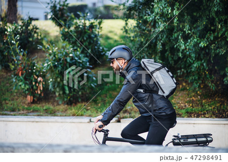 Male bicycle courier delivering packages in city. Copy space. 47298491