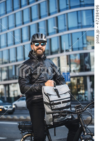 Male bicycle courier with backpack and sunglasses delivering packages in city. 47298496