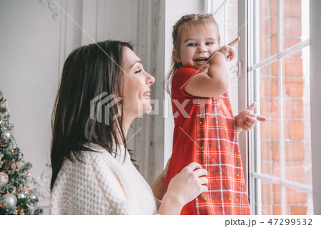 Loving mother playing with her baby girl looking at the window Loving mother playing with her baby girl looking at the window 47299532