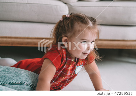 Close up little adorable thoughtful girl dreaming lying on a floor in a living room at modern home Close up little adorable thoughtful girl dreaming lying on a floor in a living room at modern home 47299535
