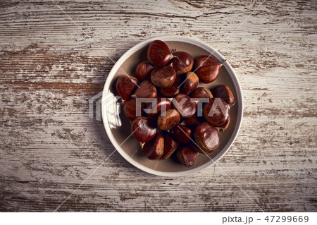 group of tasty chestnuts next to a bowl group of tasty chestnuts next to a bowl 47299669