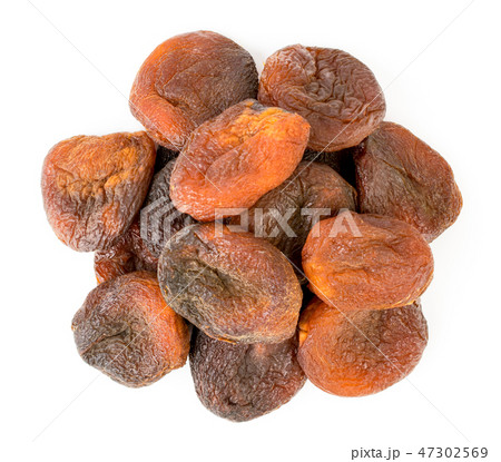 A heap of dark dried apricots on a white. The view A heap of dark dried apricots on a white. The view 47302569