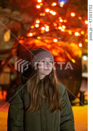 Beautiful girl looking down on the night city street against the backdrop of glowing storefront 47303702