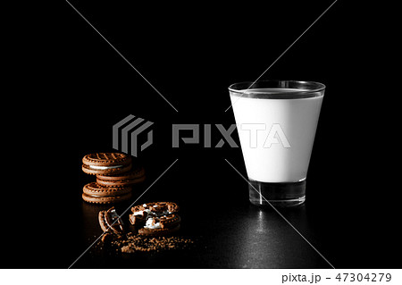 Glass of milk and chocolate cookies on black back Glass of milk and chocolate cookies on black back 47304279