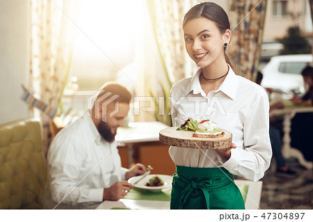 Portrait young waitress holding sandwich on plate Portrait young waitress holding sandwich on plate 47304897