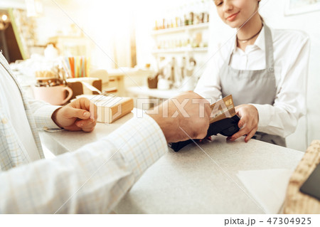 Cheerful cashier using digital device for payment Cheerful cashier using digital device for payment 47304925
