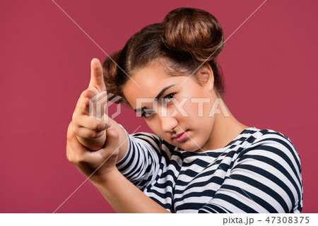 Girl pointing with finger gun gestures at camera Girl pointing with finger gun gestures at camera 47308375